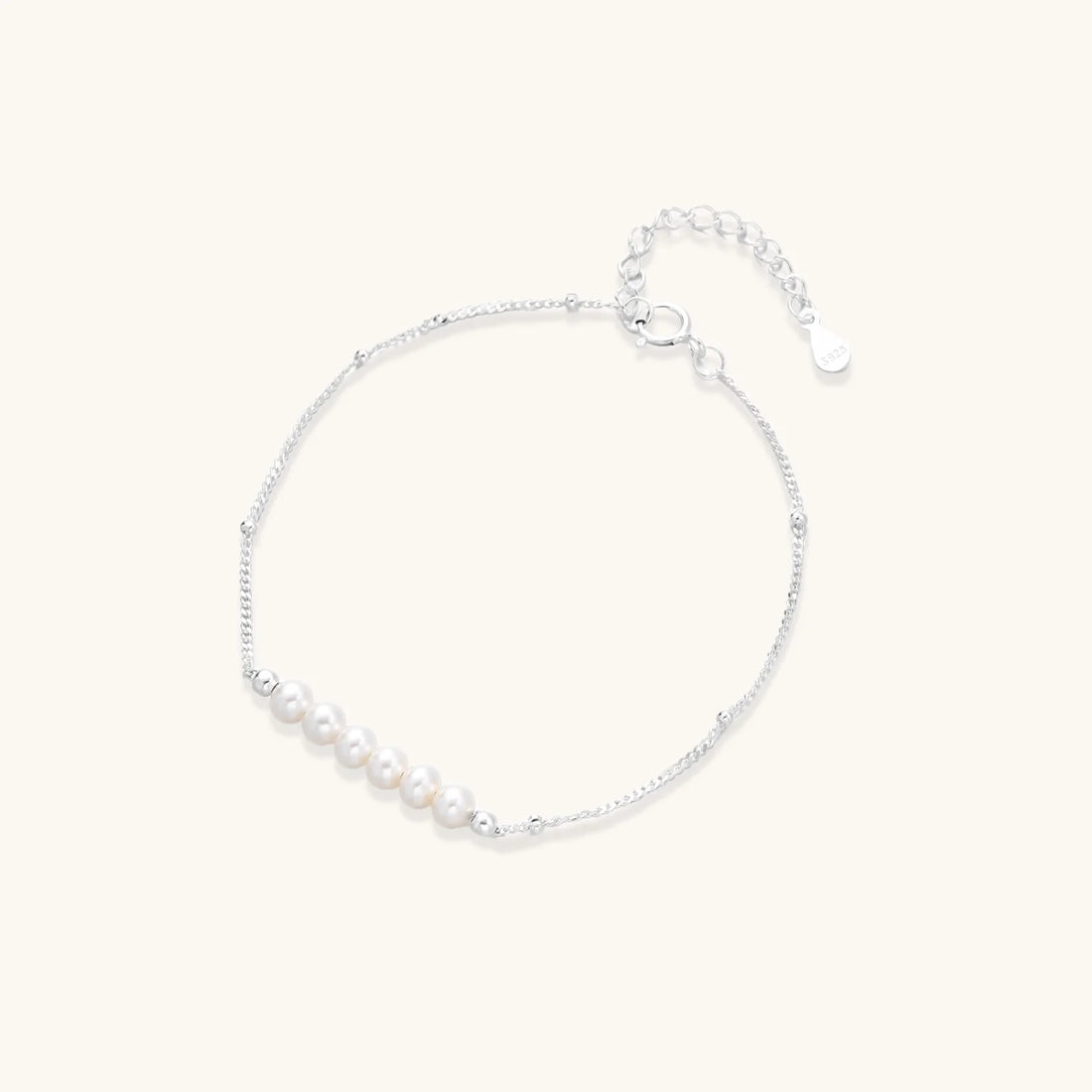 Delicate rhodium-plated silver chain bracelet with row of small baroque pearls centered on white background.