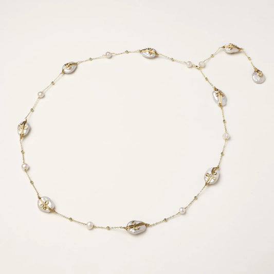 Long gold chain necklace with baroque pearls wrapped in leaf designs and small freshwater pearls spaced along the strand