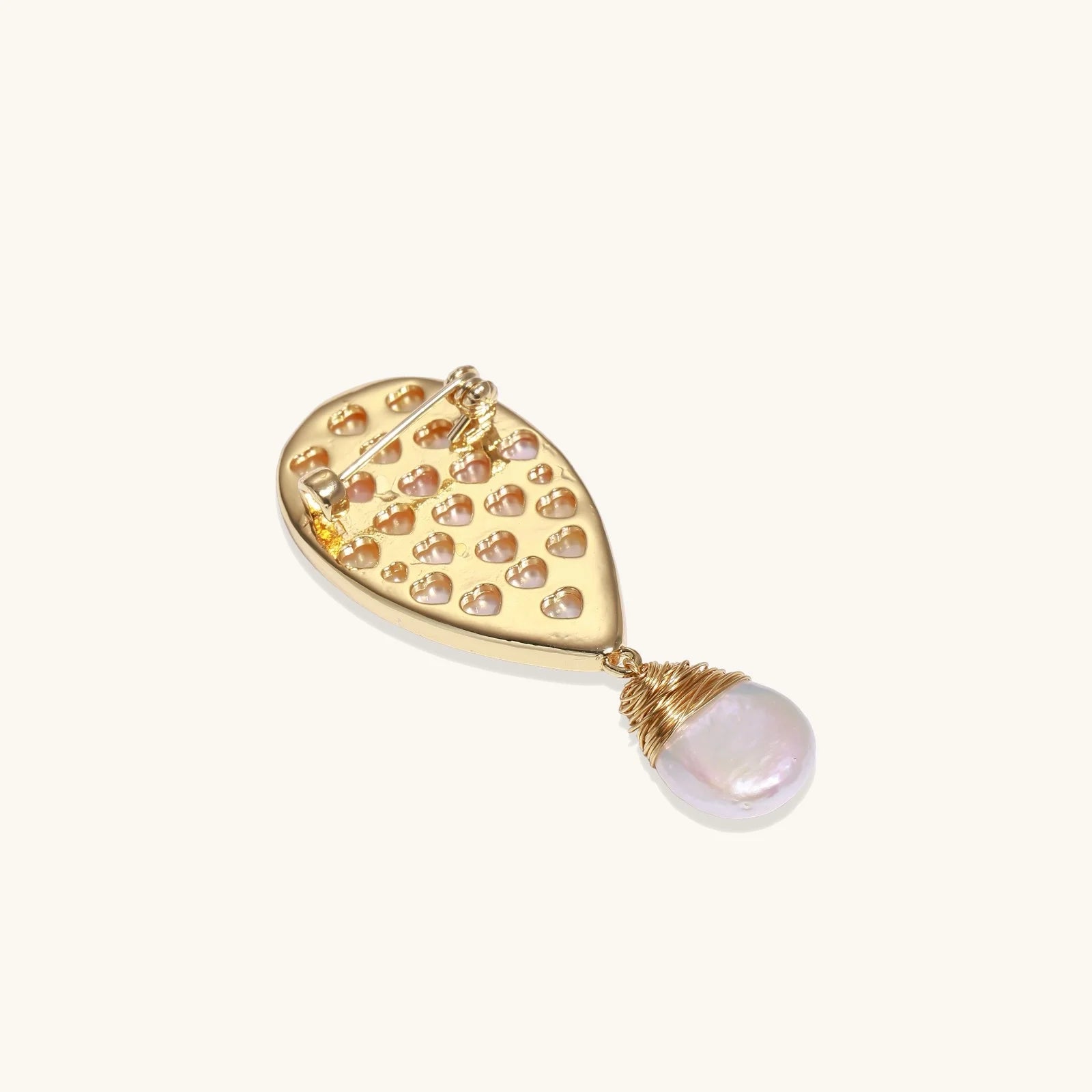 Iridescent shell brooch with gold bird accent and wire-wrapped baroque pearl drop on cream background.