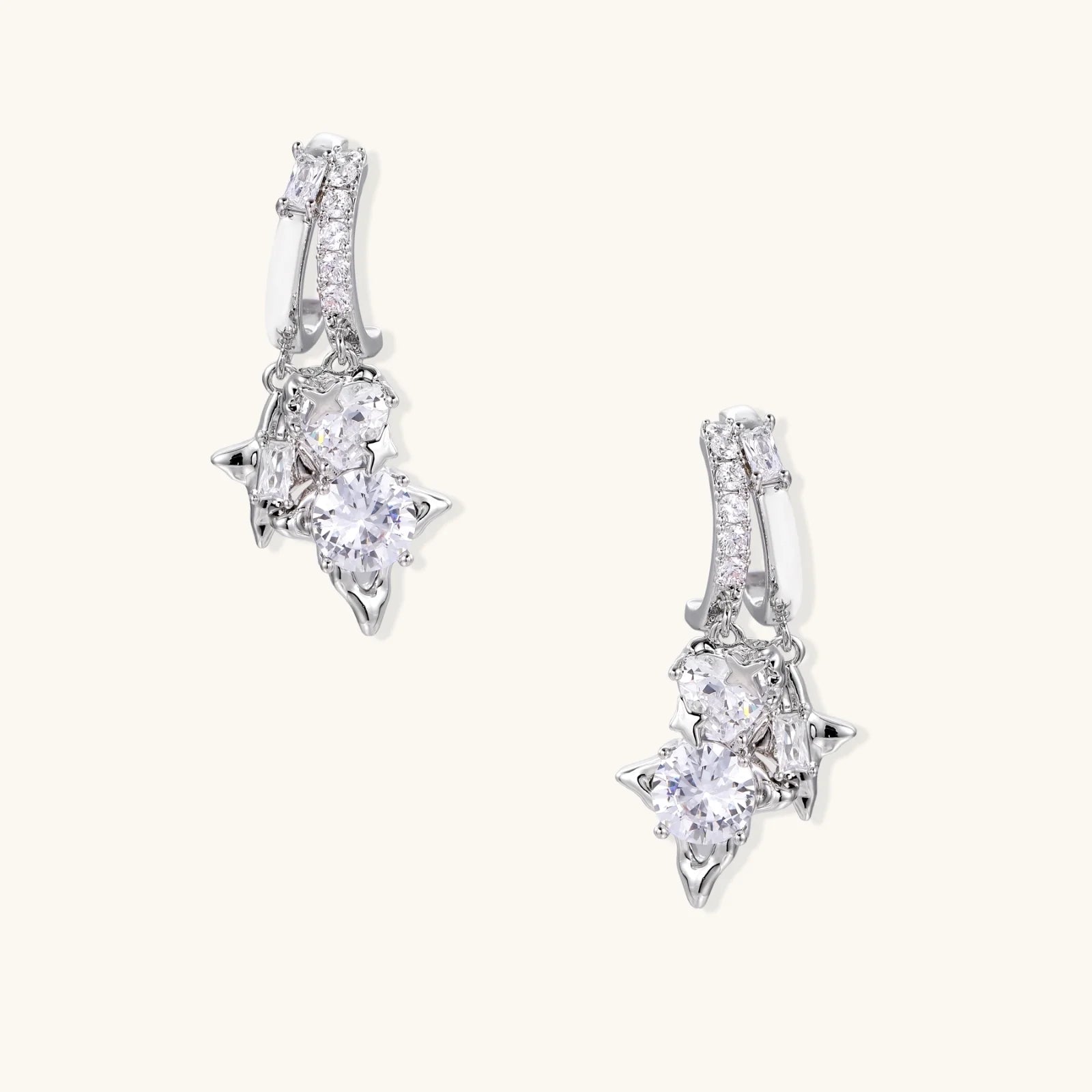 White gold-plated huggie earrings with geometric emerald-cut zirconia clusters in starburst formation on beige background
