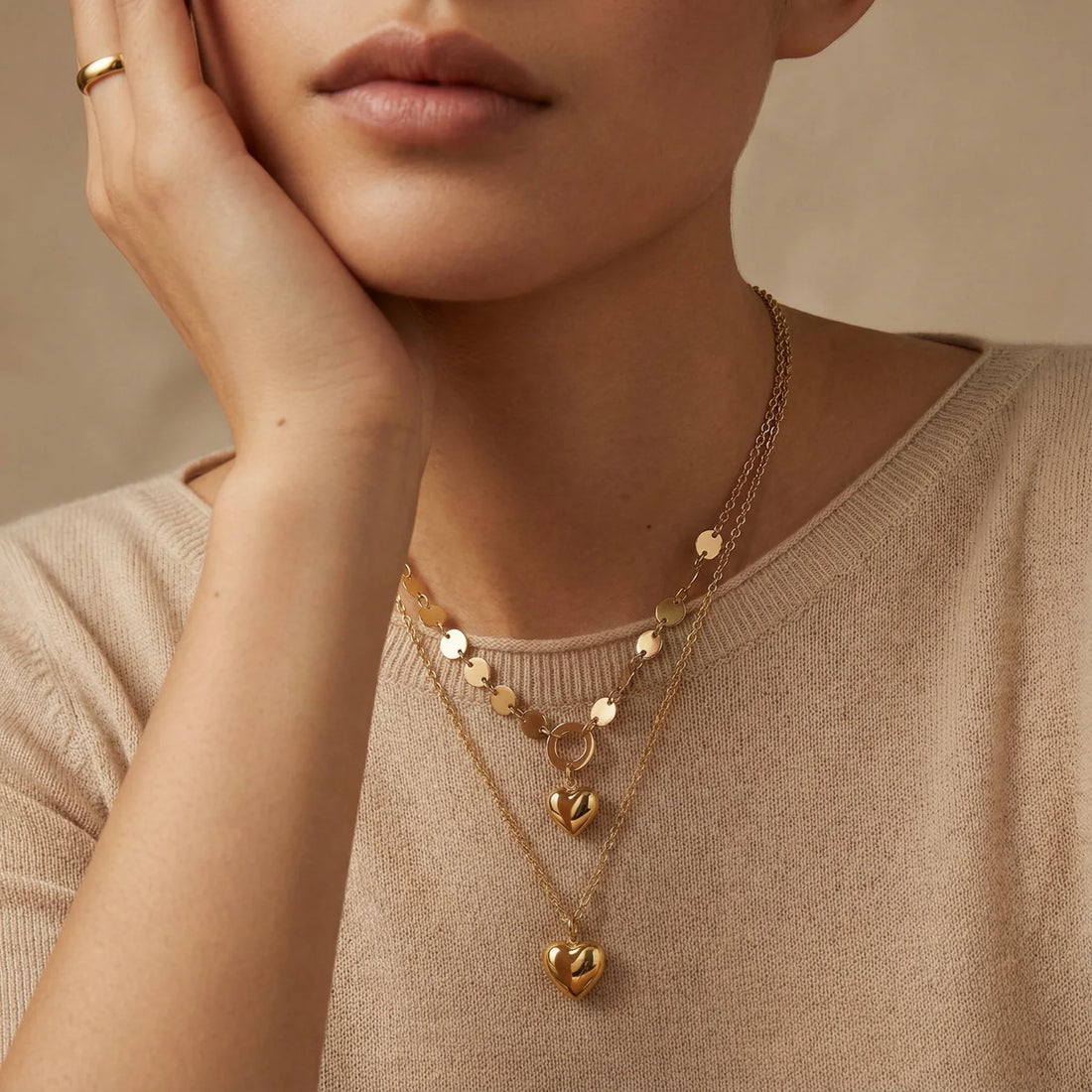 Three-layer 14K gold plated necklace with coin discs and dual heart pendants on cream background